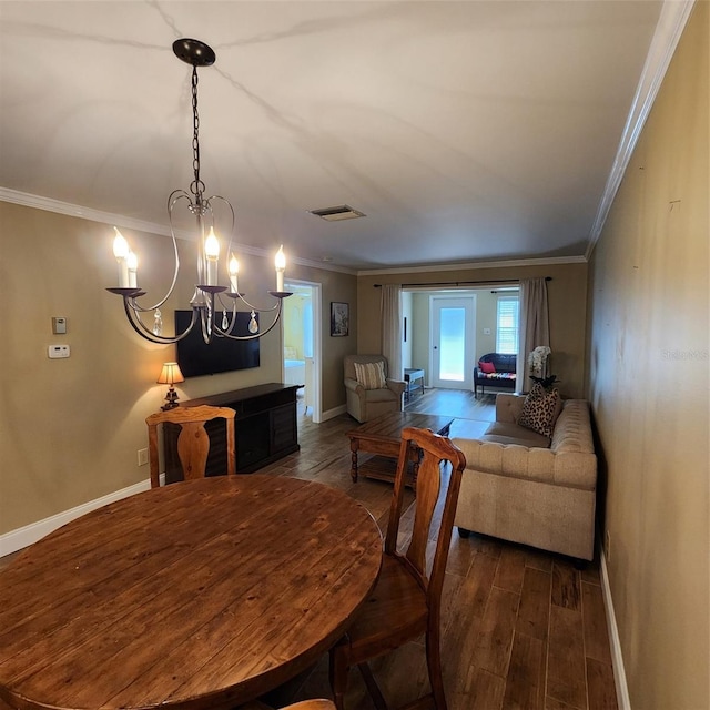 dining room with ornamental molding, dark wood-type flooring, and a chandelier