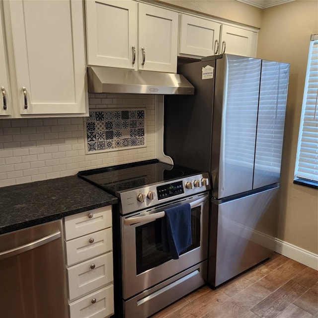 kitchen featuring decorative backsplash, light hardwood / wood-style floors, white cabinets, stainless steel appliances, and dark stone counters