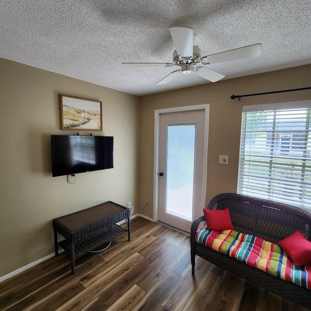 living room with a textured ceiling, dark hardwood / wood-style flooring, and ceiling fan