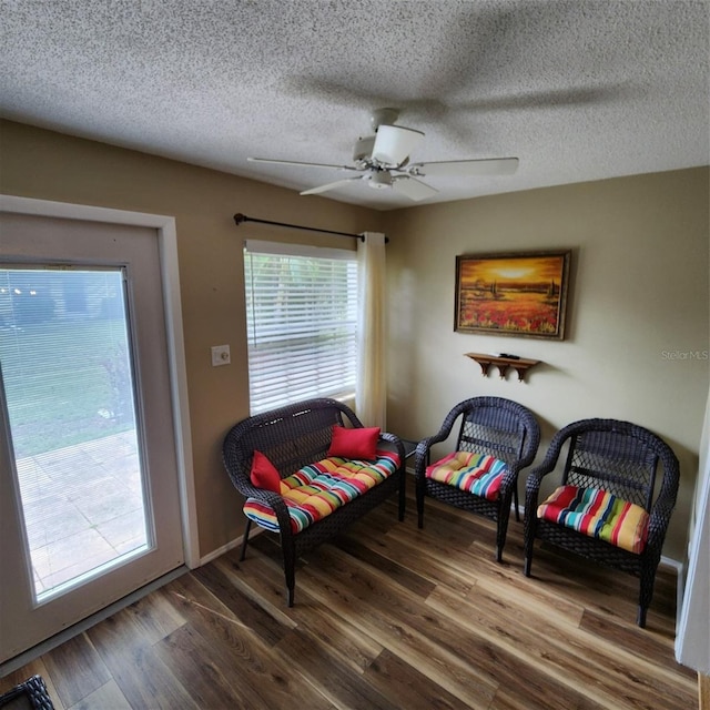 living area with ceiling fan, hardwood / wood-style flooring, and a textured ceiling