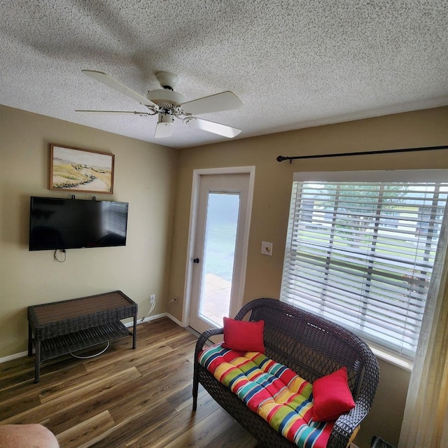 living room featuring ceiling fan, a textured ceiling, and dark hardwood / wood-style floors