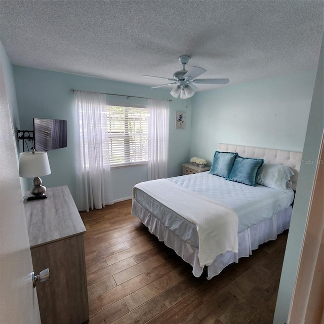 bedroom featuring ceiling fan, dark hardwood / wood-style floors, and a textured ceiling