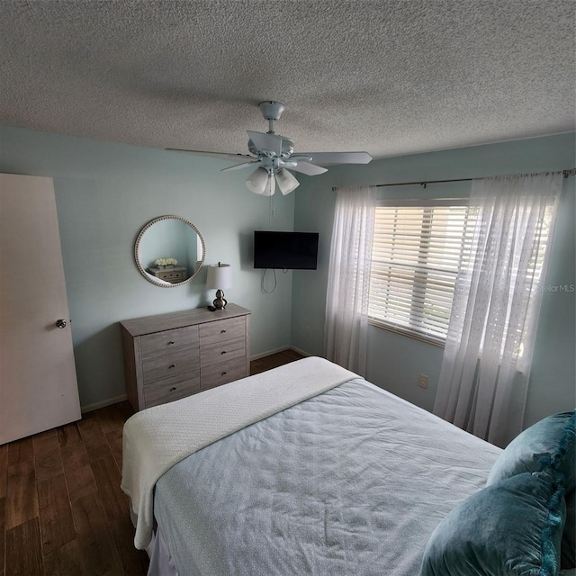 bedroom with ceiling fan, a textured ceiling, and dark hardwood / wood-style floors