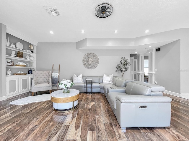 living room with built in shelves, dark hardwood / wood-style flooring, and a textured ceiling