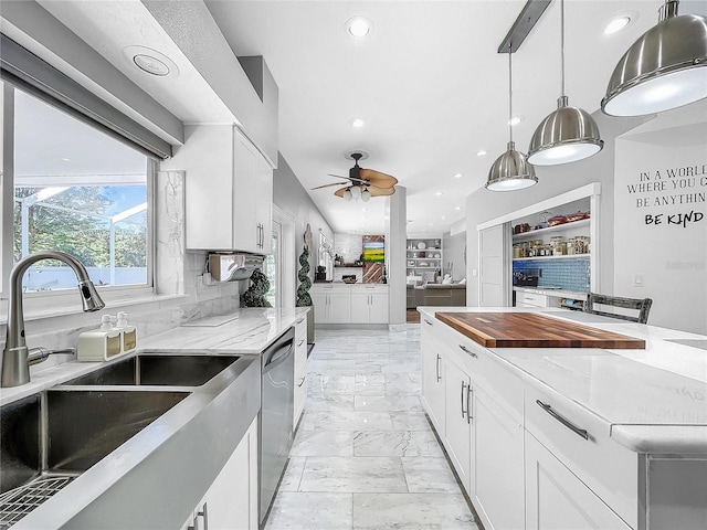 kitchen featuring white cabinets, stainless steel dishwasher, light stone countertops, and sink