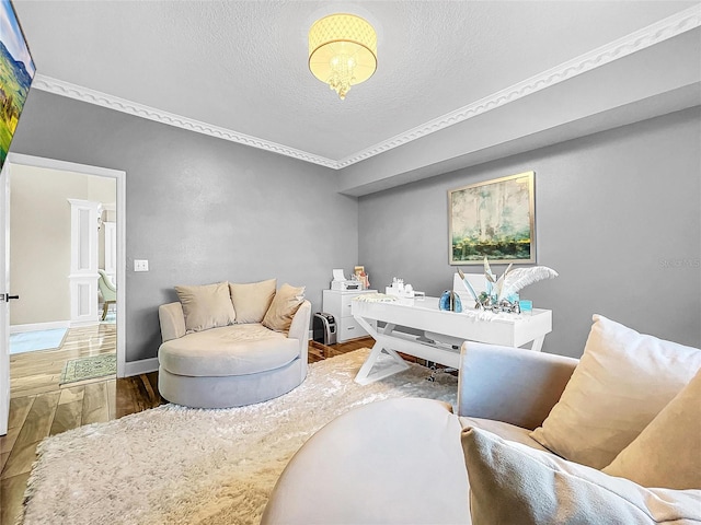 sitting room with ornamental molding, a textured ceiling, and hardwood / wood-style flooring