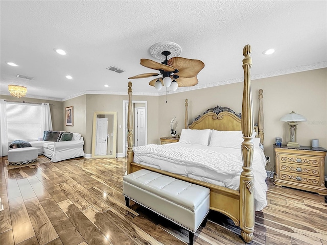 bedroom with a textured ceiling, hardwood / wood-style flooring, ceiling fan, and ornamental molding