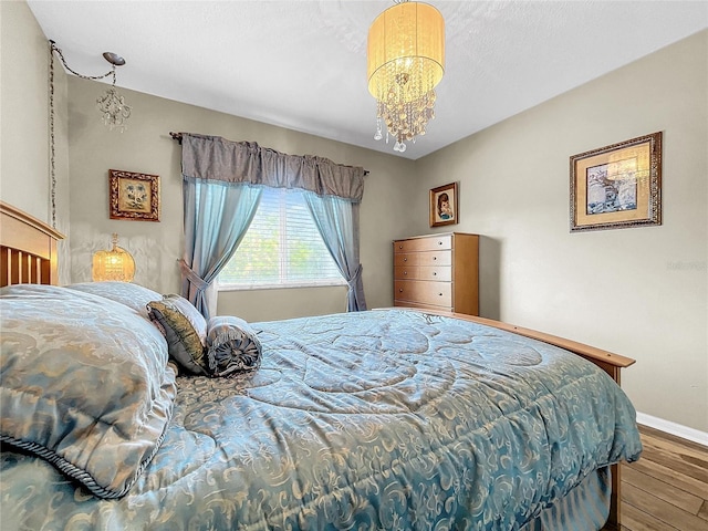 bedroom with hardwood / wood-style flooring and an inviting chandelier