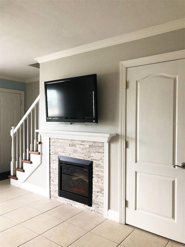 unfurnished living room with tile patterned flooring, a textured ceiling, crown molding, and a stone fireplace