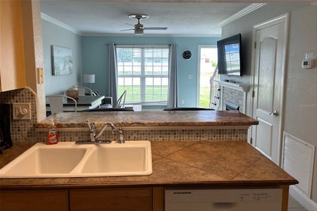 kitchen with dishwasher, sink, backsplash, ornamental molding, and ceiling fan