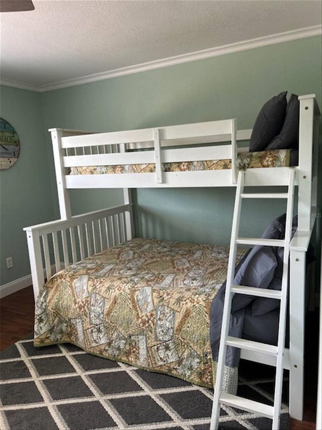 bedroom featuring a textured ceiling, dark wood-type flooring, and crown molding