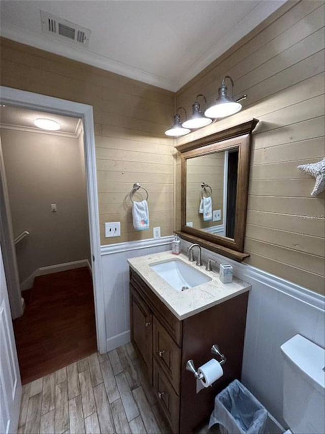 bathroom with ornamental molding, vanity, hardwood / wood-style floors, and toilet