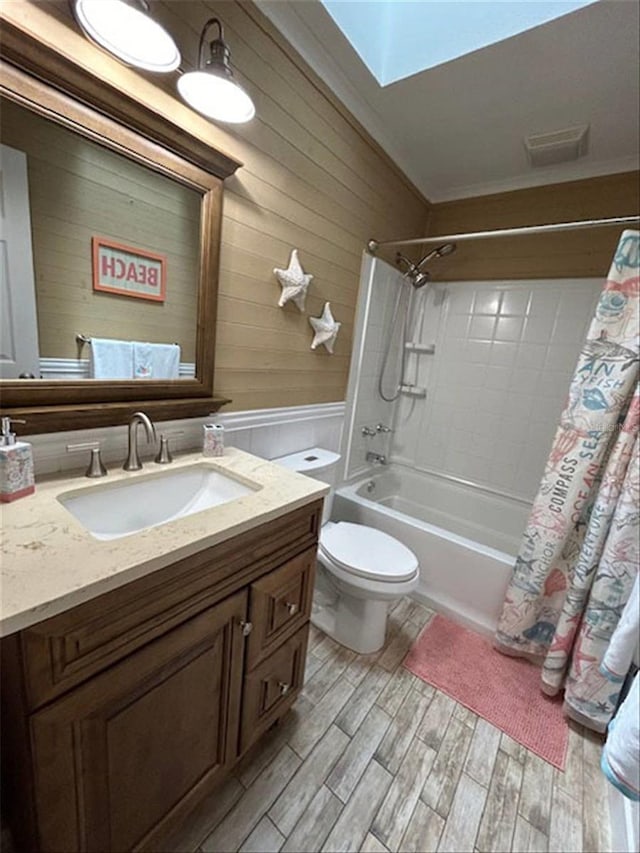 full bathroom with hardwood / wood-style floors, crown molding, shower / tub combo with curtain, vanity, and toilet