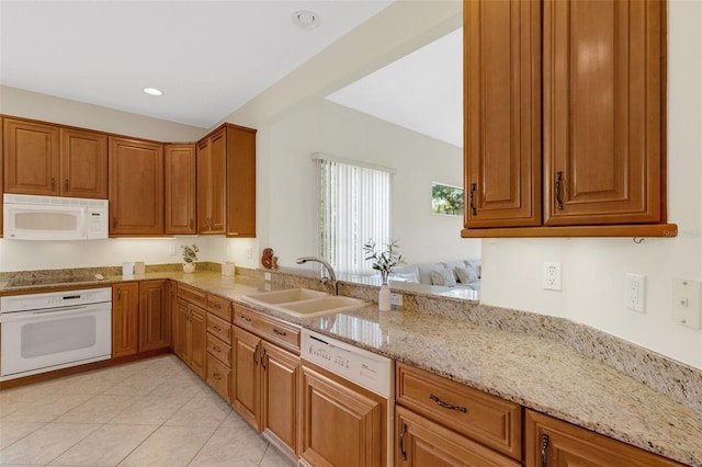 kitchen featuring sink, light stone counters, white appliances, light tile patterned floors, and kitchen peninsula