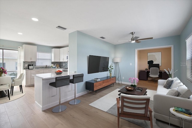 living room featuring light hardwood / wood-style floors, sink, and ceiling fan