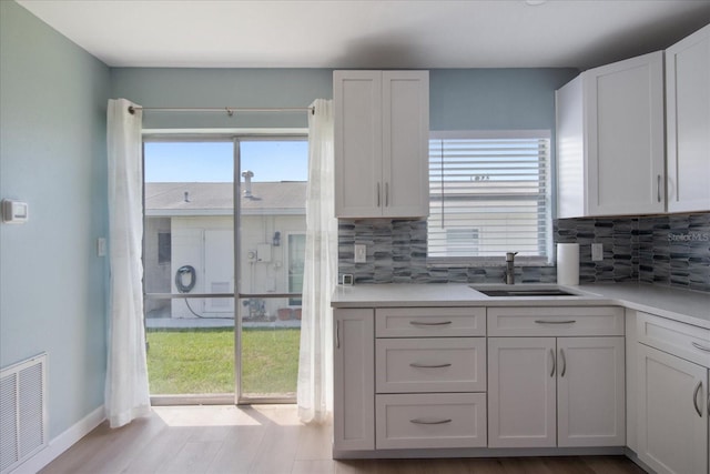 kitchen featuring decorative backsplash, white cabinets, and plenty of natural light