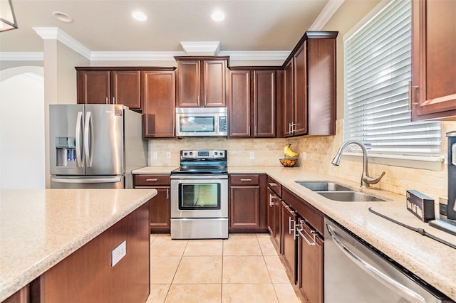 kitchen with sink, ornamental molding, appliances with stainless steel finishes, light tile patterned flooring, and light stone counters