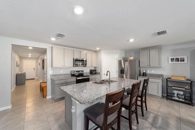 684 SE 65th Ter, Ocala, FL 34472 - kitchen featuring stainless steel appliances, a sink, gray cabinets, a breakfast bar, and a textured ceiling