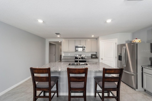 684 SE 65th Ter, Ocala, FL 34472 - kitchen featuring appliances with stainless steel finishes, a sink, light tile patterned floors, a center island with sink, and a textured ceiling