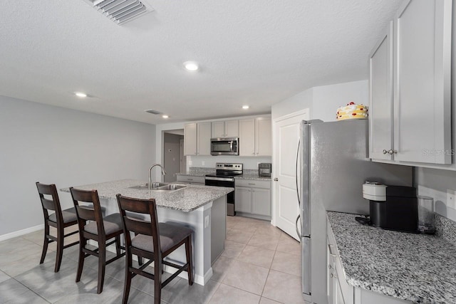 684 SE 65th Ter, Ocala, FL 34472 - kitchen featuring appliances with stainless steel finishes, a sink, a center island with sink, a kitchen bar, and light tile patterned floors