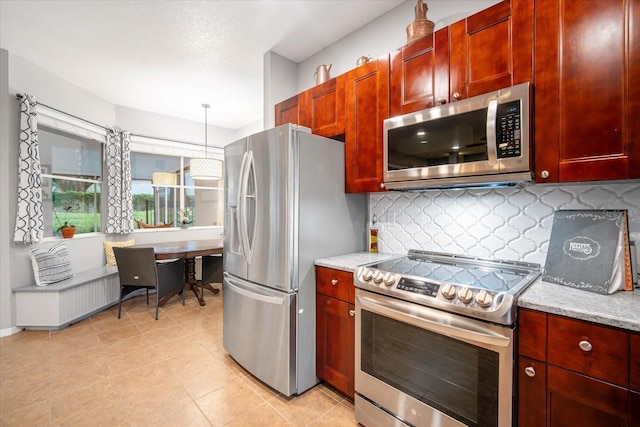 kitchen with light tile patterned flooring, hanging light fixtures, stainless steel appliances, light stone countertops, and decorative backsplash