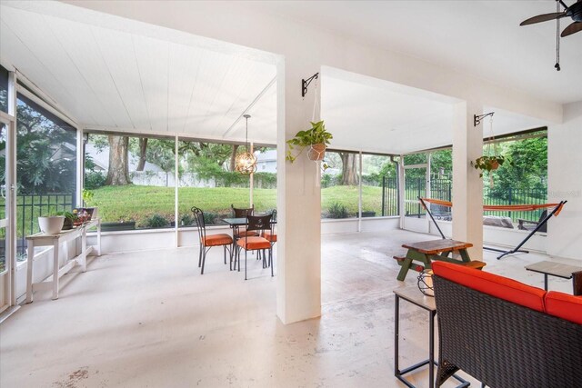 sunroom featuring ceiling fan with notable chandelier