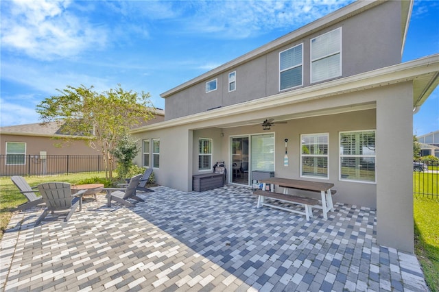 rear view of property with a patio, ceiling fan, and an outdoor fire pit