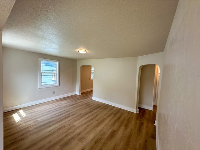 empty room featuring a textured ceiling and dark hardwood / wood-style flooring