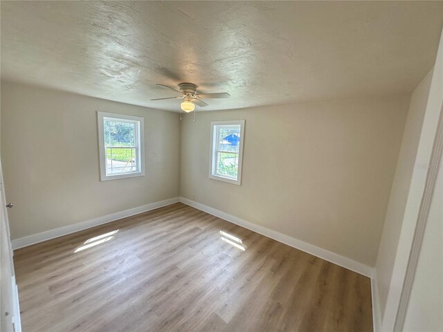 unfurnished room featuring light wood-type flooring, ceiling fan, and a textured ceiling