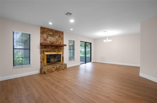 unfurnished living room with light hardwood / wood-style floors, a chandelier, and a fireplace