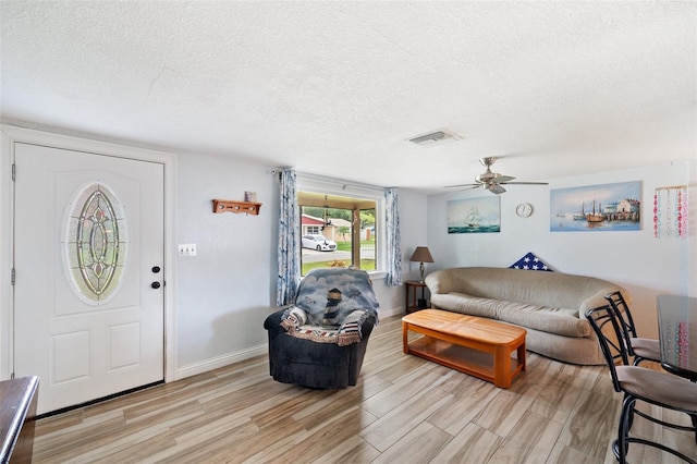 living room featuring ceiling fan, a textured ceiling, and light hardwood / wood-style floors