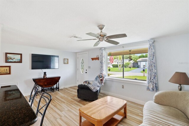 living room featuring ceiling fan, a textured ceiling, and light hardwood / wood-style floors