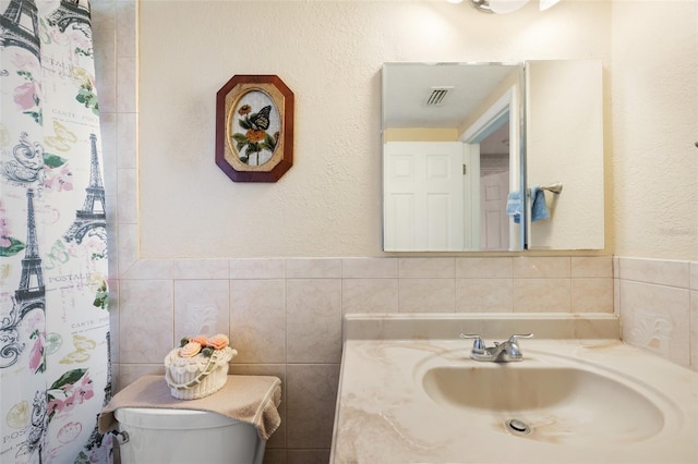 bathroom featuring tile walls, vanity, and toilet