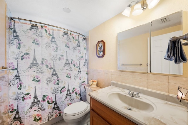 bathroom featuring tile walls, tasteful backsplash, vanity, walk in shower, and toilet