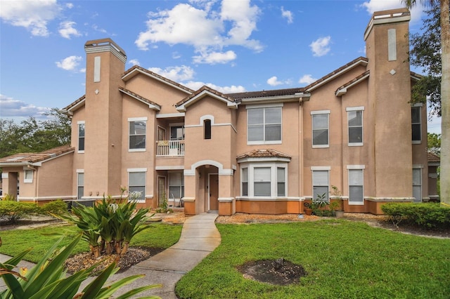 view of front of property with a balcony and a front lawn