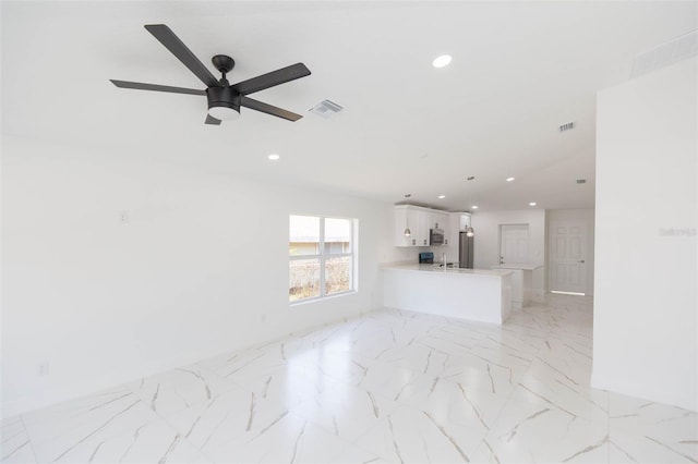 unfurnished living room featuring ceiling fan and sink