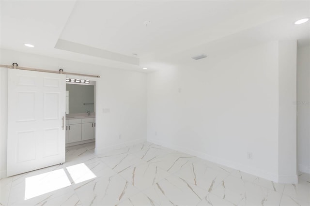 unfurnished room with a barn door and a tray ceiling