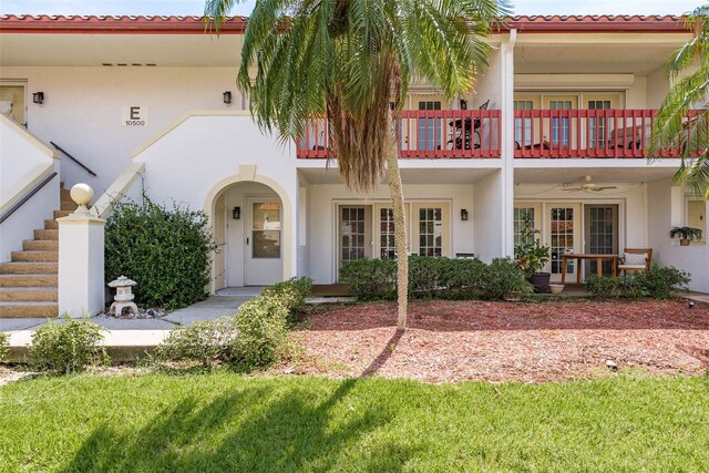 mediterranean / spanish home featuring a balcony, ceiling fan, and a front lawn