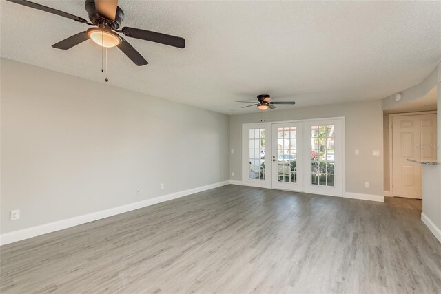 unfurnished living room with a textured ceiling, light hardwood / wood-style floors, ceiling fan, and french doors