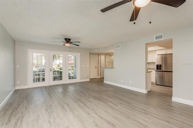 unfurnished living room with a textured ceiling, light hardwood / wood-style floors, and ceiling fan