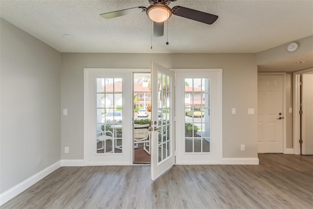 doorway featuring light wood-type flooring, ceiling fan, and a textured ceiling