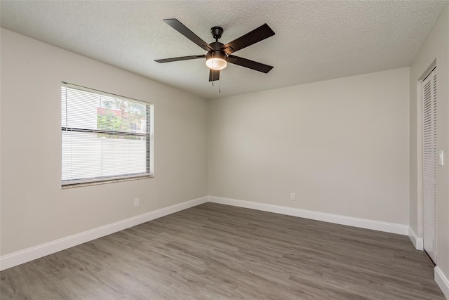 unfurnished bedroom with a textured ceiling, dark hardwood / wood-style flooring, ceiling fan, and a closet