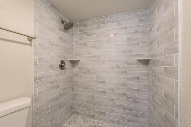 bathroom featuring tiled shower and toilet