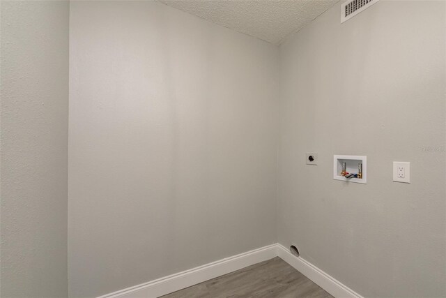 laundry room featuring hookup for a washing machine, a textured ceiling, hardwood / wood-style floors, and electric dryer hookup