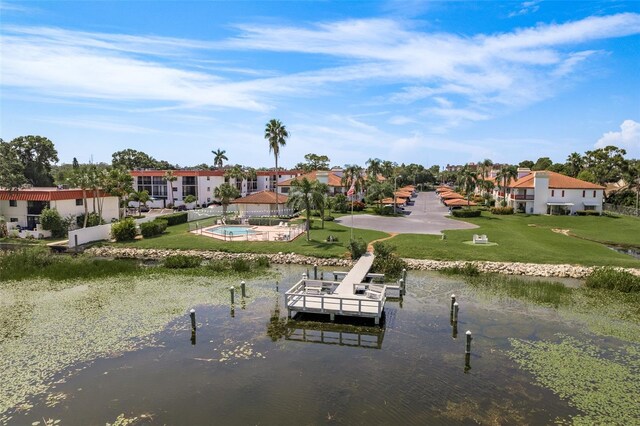 view of dock with a lawn and a water view