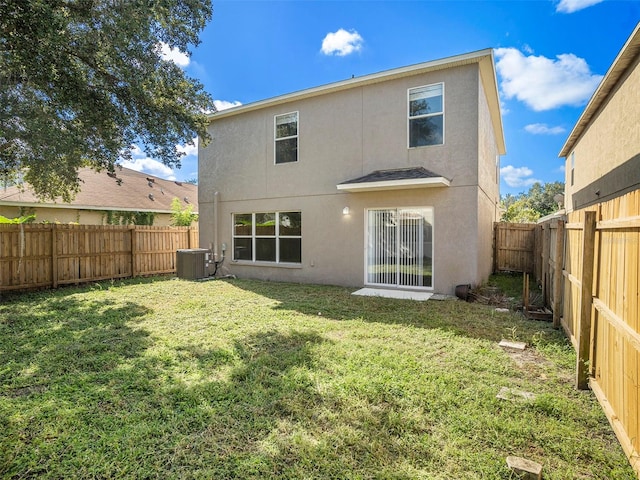 back of property with central air condition unit and a yard