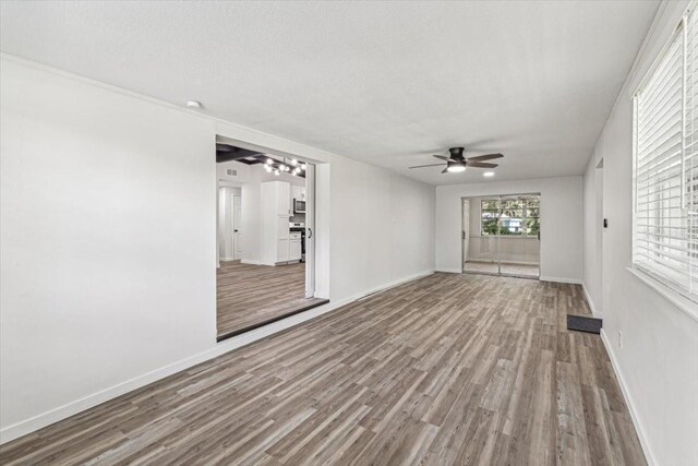 interior space with ceiling fan, baseboards, wood finished floors, and a textured ceiling