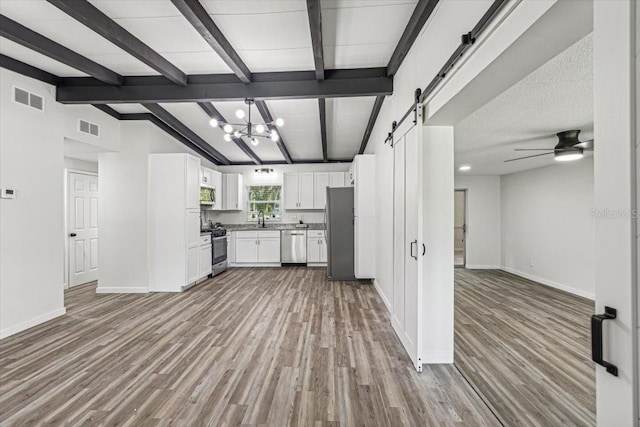 kitchen featuring a barn door, white cabinetry, light hardwood / wood-style flooring, and stainless steel appliances