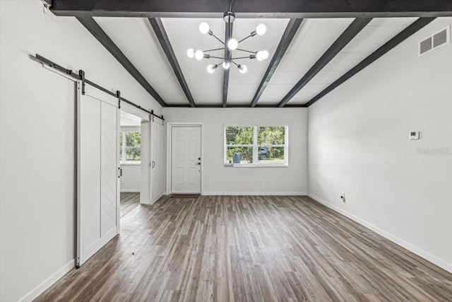 unfurnished living room featuring a barn door, wood-type flooring, beam ceiling, and a notable chandelier