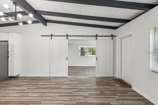 interior space with wood-type flooring, vaulted ceiling with beams, plenty of natural light, and a barn door